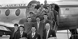 Чёрно-белая фотография одетых в костюмы мужчин на трапе самолёта.